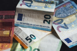 20, 50, and 100 euro banknotes are scattered around, overlapping each other with slight wrinkles and creases.