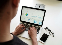 A person intently reviewing data visualisations on a laptop dashboard, showcasing real-time access to key metrics.