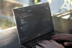 Close-up of hands on a laptop with code on the screen, indicating automated fund distribution through APIs.