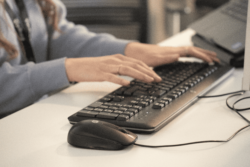 Close-up of a person's hand on a keyboard, representing manual payment processing.