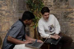 Two colleagues collaborating on laptops in a modern workspace, discussing ideas and reviewing work together.