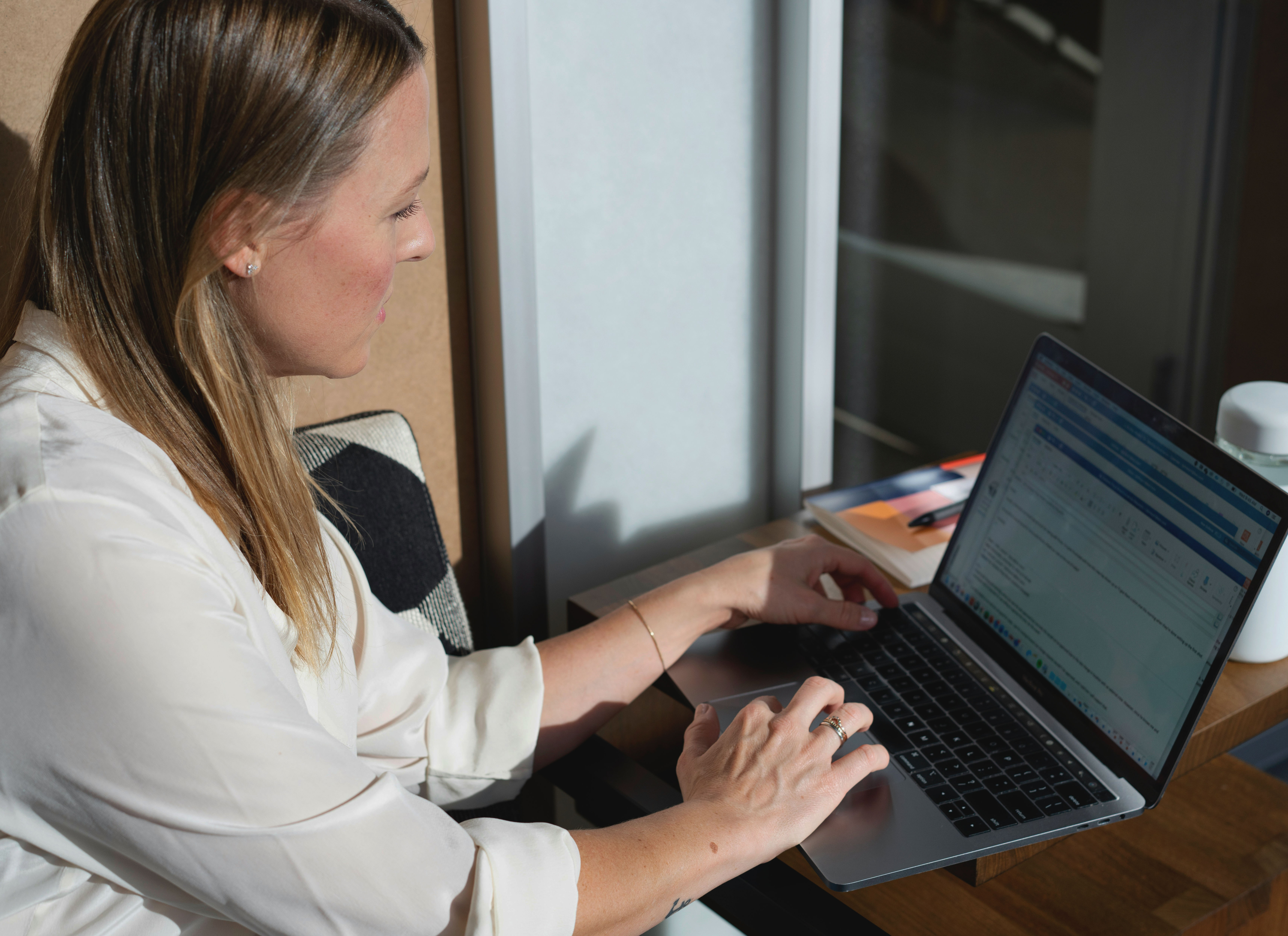 A woman sitting and typing on her laptop while looking at the screen.