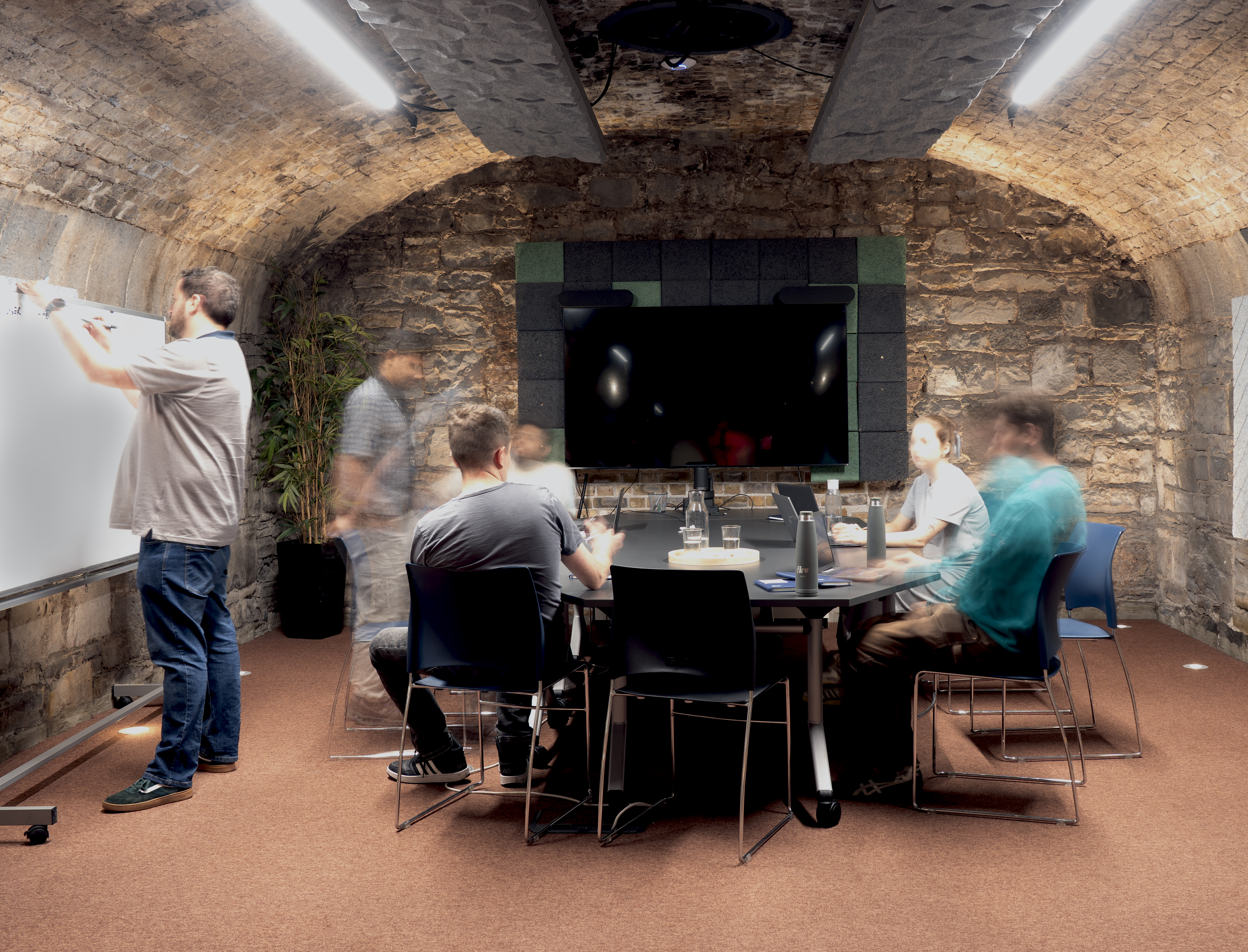 Meeting room full of people, moving around.