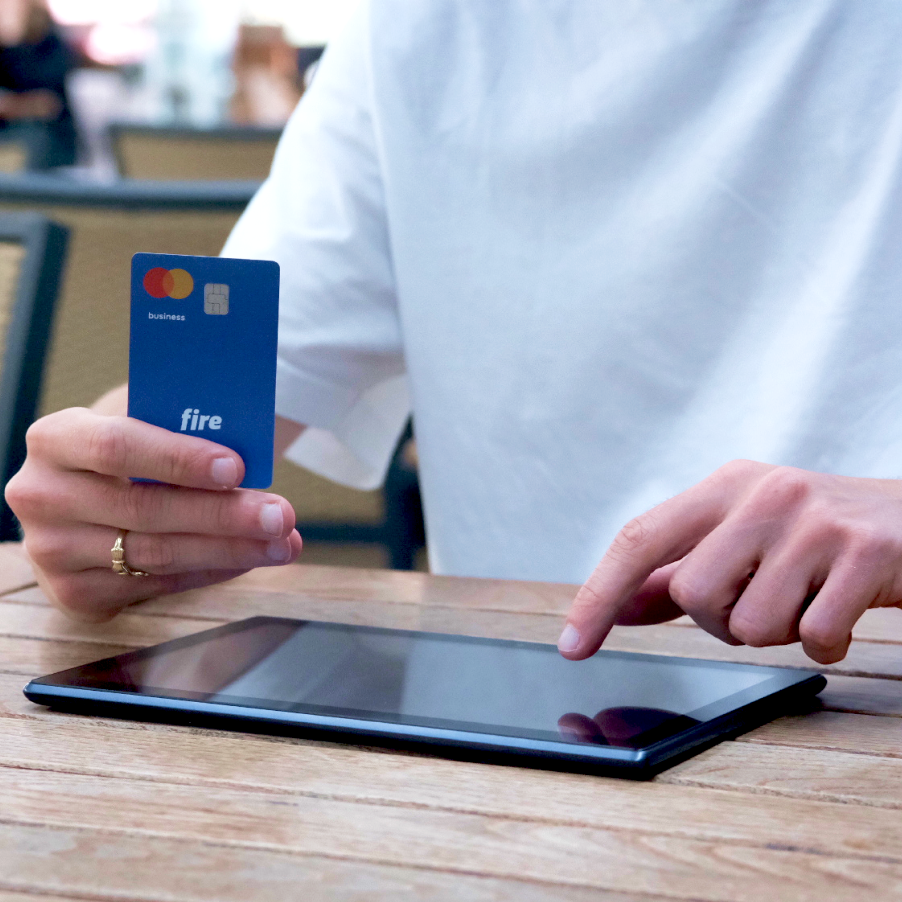 Person holding a tablet with a Fire card on a wooden table.